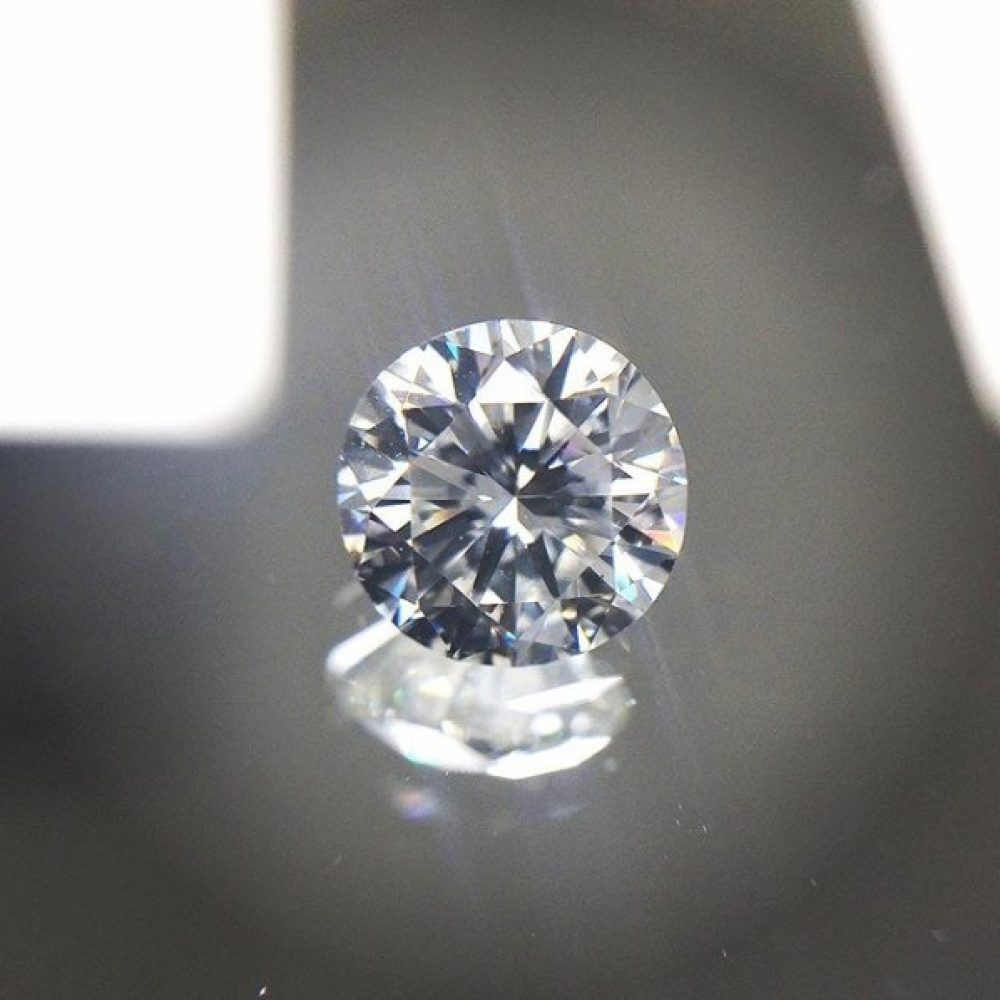 loose white triple excellent round cut diamond against a mirror